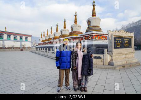 Une famille à l'entrée du monastère de Ta'ER, devant huit stupas, représentait les huit étapes de la vie de Bouddha. Banque D'Images