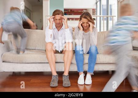 Les enfants méchants, hyperactifs et énergiques agaçant leur mère et leur père à la maison. Les parents fatigués et stressés souffrent de maux de tête et de fatigue Banque D'Images