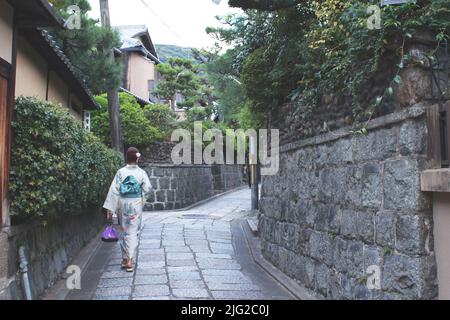 Une japonaise portant un yukata marchant le long d'une rue étroite à Kyoto, au Japon. Banque D'Images