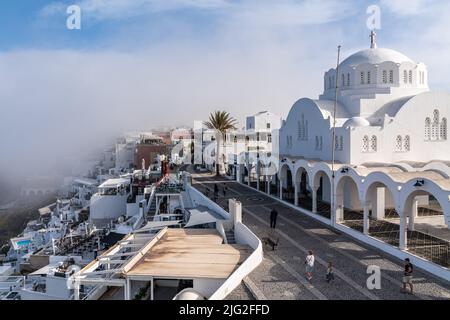 Vue sur Fira et la cathédrale orthodoxe métropolitaine, parmi les nuages bas pittoresques en début de matinée Banque D'Images