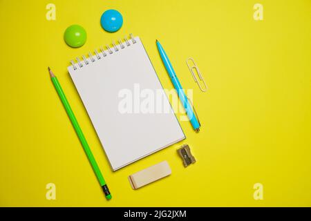 Vue de dessus photo Ouvrir le bloc-notes stylo à bille sur fond jaune avec espace de copie. Minimaliste plat de retour à l'école. Banque D'Images