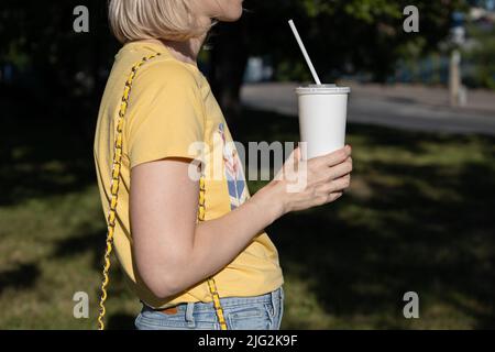 main de femme tenant un verre de papier blanc avec une paille Banque D'Images