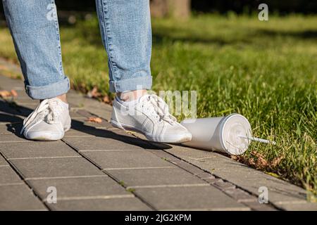 le pied pousse un verre à cocktail jetable vide hors du trottoir Banque D'Images