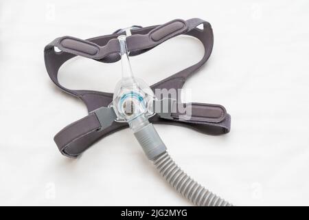Connexion d'un masque CPAP et d'un harnais à un tuyau CPAP sur un drap de lit blanc Banque D'Images