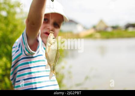 Un garçon attrape un poisson. Un enfant sur le lac pêche Banque D'Images