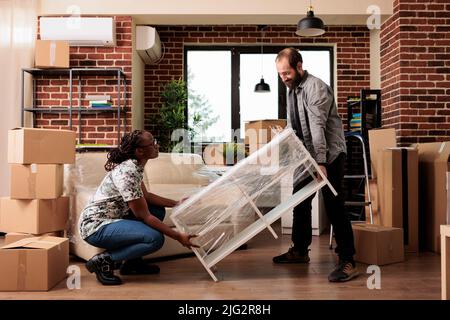 Divers couple décorant nouvel appartement loué pour se déplacer et profiter de la réinstallation ensemble, s'installer dans la propriété de maison. Se sentir heureux de l'événement de la vie après avoir acheté la maison pour la vie future. Banque D'Images