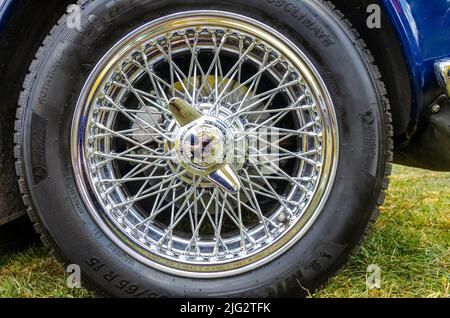 Un cliché d'une roue d'un Triumph TR6 avec des rayons chromés complexes formant un treillis et se rencontrant dans un moyeu central Banque D'Images