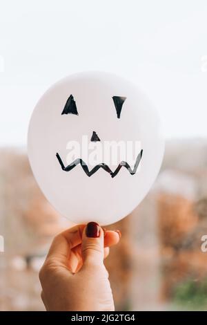 Les jacks peints font face aux ballons. Préparation des boules orange et blanches pour halloween. Activités à la maison pour Halloween. Jouets faits main Banque D'Images