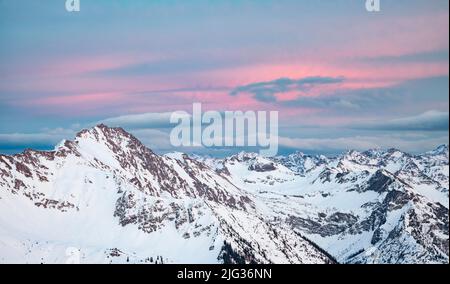 Des nuages colorés sur une chaîne de montagnes enneigée au coucher du soleil en hiver. Allgau Alpes, Bavière, Allemagne Banque D'Images