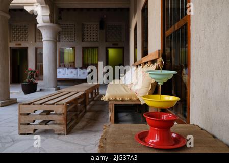 Place assise dans une cour ouverte d'une maison arabe traditionnelle. Chaises en bois et caisses pour tables. Panier de fruits audacieux et coloré au premier plan. Banque D'Images