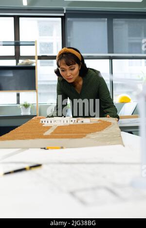 Jeune architecte asiatique examinant le modèle architectural au bureau Banque D'Images