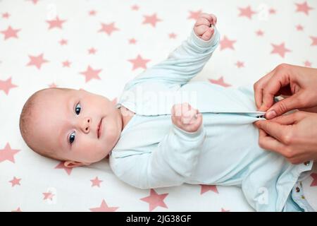 Mère habillant son bébé à la maison Banque D'Images