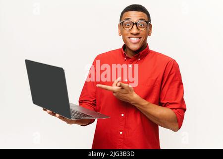 Portrait de l'homme surpris choqué tenant un ordinateur portable et regardant l'appareil photo avec de grands yeux étonnés. Studio d'intérieur isolé sur fond blanc Banque D'Images