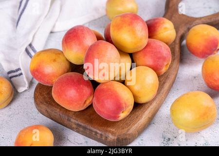 Abricots frais. Abricots mûrs dans un plat de service en bois sur fond de pierre. Abricots en vrac. Gros plan Banque D'Images