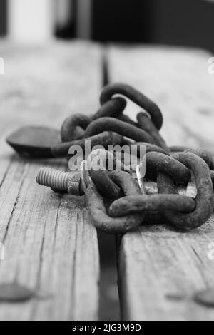 Chaîne de résistance industrielle à usage intensif posée sur une table en bois en noir et blanc. Banque D'Images