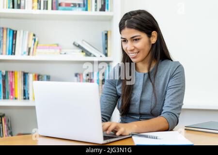 Belle femme sud-américaine travaillant à l'ordinateur au bureau Banque D'Images