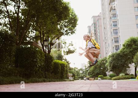 Écolière de retour à l'école après les vacances d'été. Enfant en uniforme souriant tôt le matin à l'extérieur. Banque D'Images