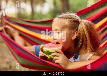 Petite fille mignonne reposant dans un hamac coloré dans la forêt Banque D'Images