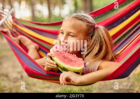 Petite fille mignonne reposant dans un hamac coloré dans la forêt Banque D'Images