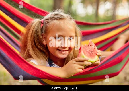 Petite fille mignonne reposant dans un hamac coloré dans la forêt Banque D'Images