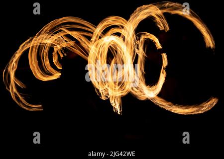 Cercles de flammes dans l'obscurité. Spectacle de tir à une vitesse d'obturation longue. Flammes. Feu sur fond noir. Banque D'Images