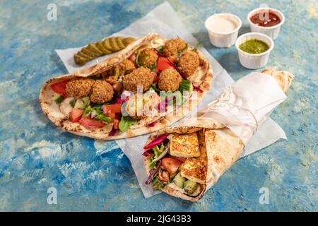 Traditionnel méditerranéen arabe halloumi et falafel grillé, houmous et légumes dans des roulés de pain plat avec des herbes et une variété de sauces Banque D'Images