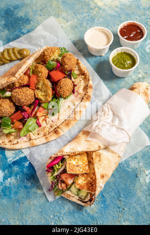 Traditionnel méditerranéen arabe halloumi et falafel grillé, houmous et légumes dans des roulés de pain plat avec des herbes et une variété de sauces Banque D'Images