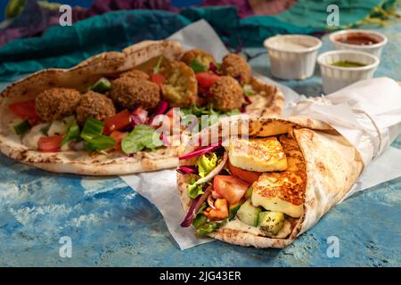 Traditionnel méditerranéen arabe halloumi et falafel grillé, houmous et légumes dans des roulés de pain plat avec des herbes et une variété de sauces Banque D'Images