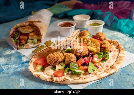 Traditionnel méditerranéen arabe halloumi et falafel grillé, houmous et légumes dans des roulés de pain plat avec des herbes et une variété de sauces Banque D'Images