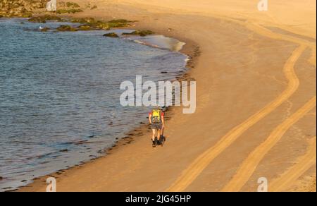 Un randonneur solitaire marchant le long du bord de l'eau sur une plage Santander Cantabria Espagne Banque D'Images