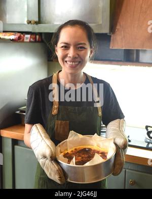 Une femme vietnamienne tenant un gâteau frais au four mitt Banque D'Images