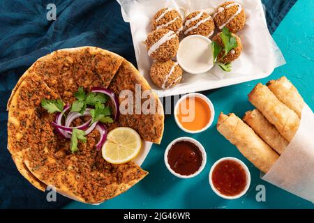 Pizza marocaine traditionnelle méditerranéenne pain plat recouvert de lentilles rouges, de falafel et de petits pains au fromage servis avec des trempettes Banque D'Images