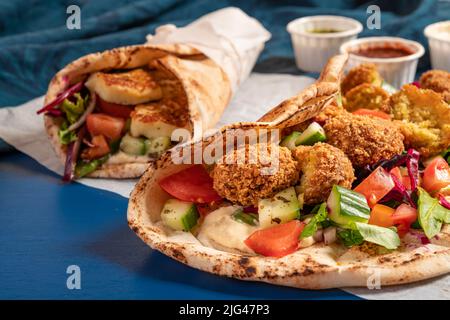 Traditionnel méditerranéen arabe halloumi et falafel grillé, houmous et légumes dans des roulés de pain plat avec des herbes et une variété de sauces Banque D'Images