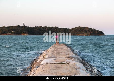 La tortue s'enchaîne au coucher du soleil avec deux personnes pêchant à Buzios, Brésil. Pêche à Buzios, Brésil. Banque D'Images