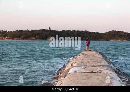 La tortue s'enchaîne au coucher du soleil avec deux personnes pêchant à Buzios, Brésil. Pêche à Buzios, Brésil. Banque D'Images