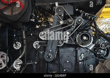 Vue rapprochée des mécanismes de la moissonneuse-batteuse avec chaînes en fer, groupes moteurs et circuits hydrauliques. Machines agricoles en cours de production et d'assemblage. Banque D'Images