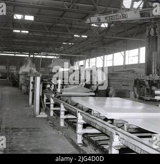 1950s, historique, deux sidérurgistes manipulant des tôles d'acier finies à l'aciérie Steel Company of Wales Abbey à Port Talbot, pays de Galles. ROYAUME-UNI. L'acier pressé et l'acier en fer blanc pour usage domestique et la fabrication de voitures automobiles étaient tous deux des produits de ces géants industriels. Banque D'Images