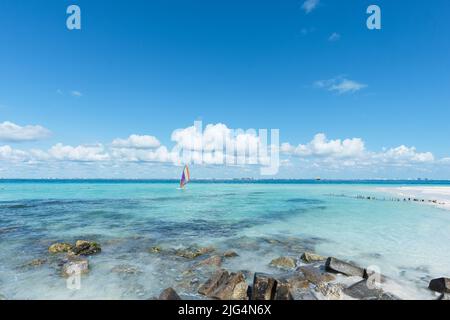 Homme méconnaissable planche à voile près d'une plage tropicale à Isla Mujeres, au Mexique. En arrière-plan se trouve le ciel bleu. Concept sports vacances Banque D'Images