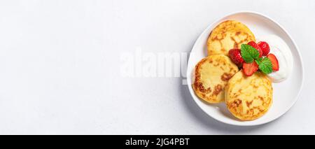 Crêpes au fromage cottage avec fraises fraîches, menthe et crème sur fond gris. Banque D'Images
