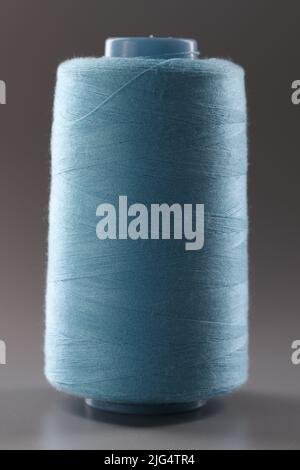 Texture du fil bleu dans la bobine de couture sur fond gris. gros plan Banque D'Images