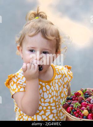 L'enfant mange des baies dans le jardin. Mise au point sélective. Enfant. Banque D'Images