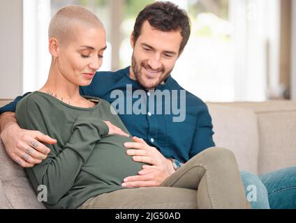 Je suis enthousiaste à l'idée de rencontrer leur petit-enfant. Photo courte d'un jeune couple expectant affectueux assis sur le canapé à la maison. Banque D'Images