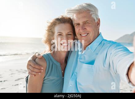 Je m'amuse toujours avec vous à mes côtés. Photo d'un couple adulte prenant un selfie sur la plage. Banque D'Images
