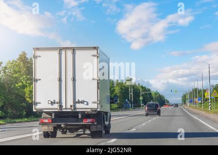 Mini-camion roulant sur l'autoroute par temps ensoleillé. Blanc livraison moderne livraison de petite cargaison camion de messagerie se déplaçant rapidement sur la route d'autoroute à la ville banlieue urbaine Banque D'Images