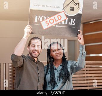 Nous l'avons fait. Photo d'un jeune couple tenant une planche vendue à l'extérieur de leur maison. Banque D'Images