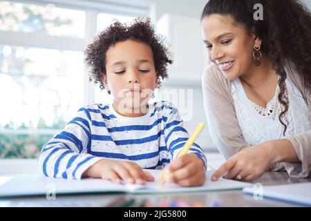HES vraiment talentueux. Photo d'une mère aidant son fils à faire ses devoirs à la table de cuisine. Banque D'Images