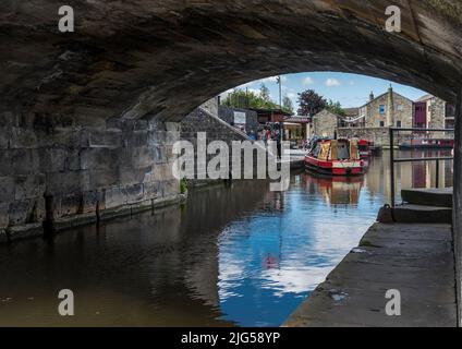 Des bateaux étroits sur le canal Leeds-Liverpool - Springs Branch Canal à la jonction des deux canaux encadrés par l'arche d'un vieux pont en pierre. Banque D'Images