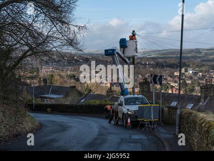 Technicien d'ingénierie de télécommunications travaillant sur une plate-forme de travail mobile surélevée en bord de route pour reconnecter les fils à un boîtier de raccordement monté sur poteau. Banque D'Images