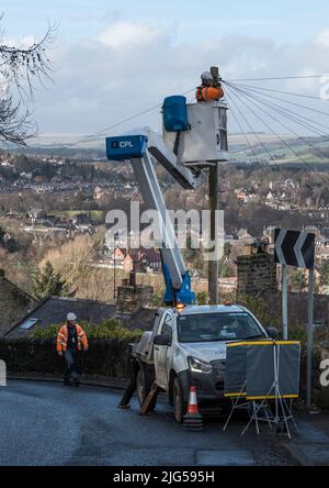 Technicien d'ingénierie de télécommunications travaillant sur une plate-forme de travail mobile surélevée en bord de route pour reconnecter les fils à un boîtier de raccordement monté sur poteau. Banque D'Images