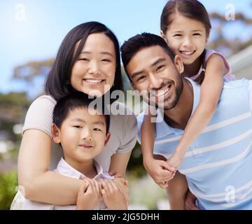 C'est du vrai bonheur. Photo d'une jeune famille passant du temps ensemble dans son jardin à la maison. Banque D'Images